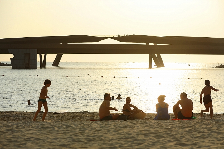 Du khách nước ngoài thư giãn tại bãi biển Sunset Town, nhìn ra Cầu Hôn